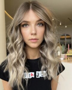 Woman with balayage hair in a black shirt, showcasing the 'Dimensional Balayage' service at Kasey Lee Blonde Specialist